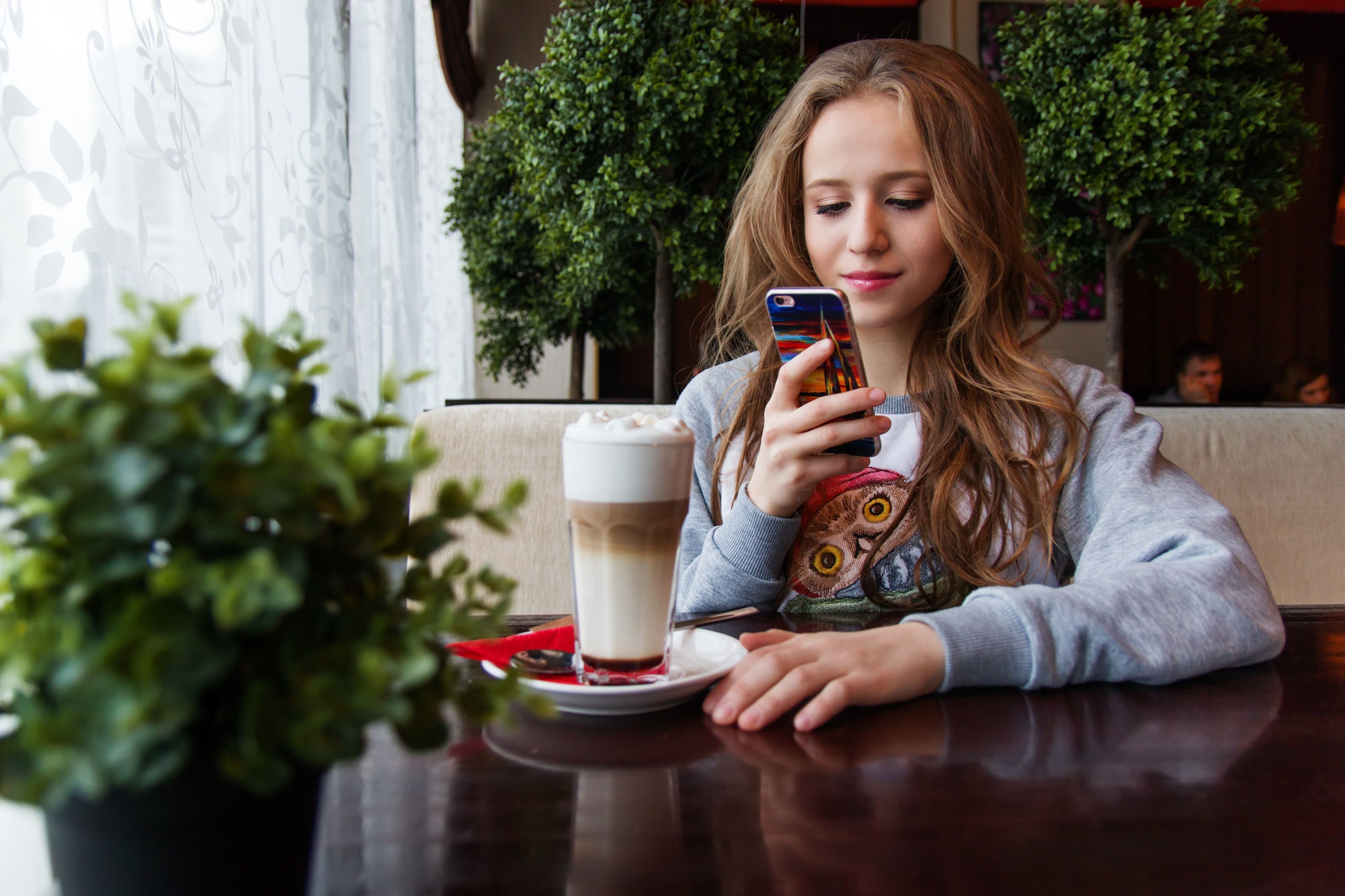 Cliente installée dans un café qui consulte son téléphone