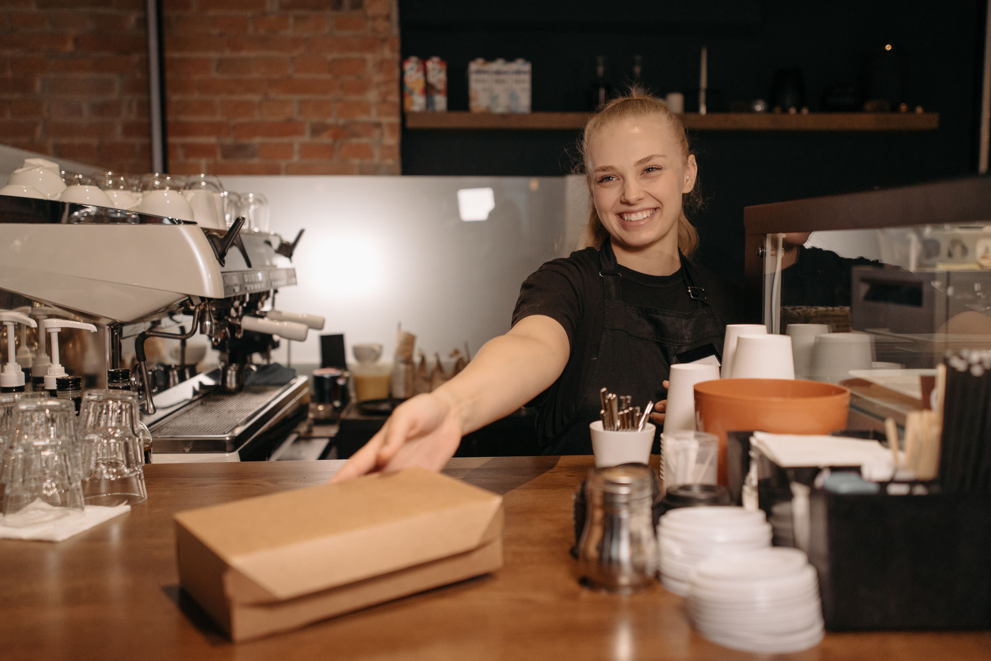 Barista souriant qui tend une commande à emporter au comptoir