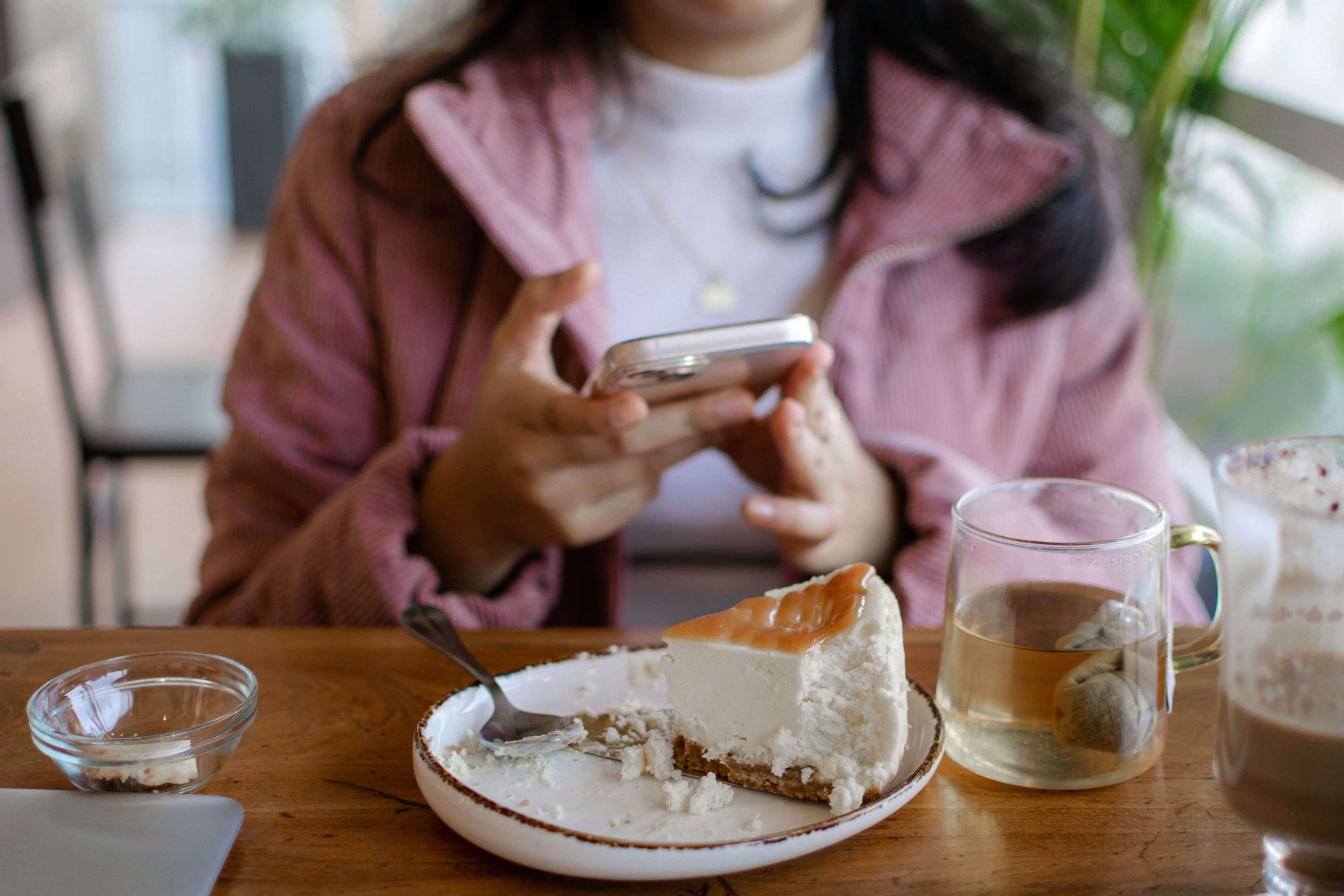 Cliente qui photographie une part de cheesecake avec son téléphone